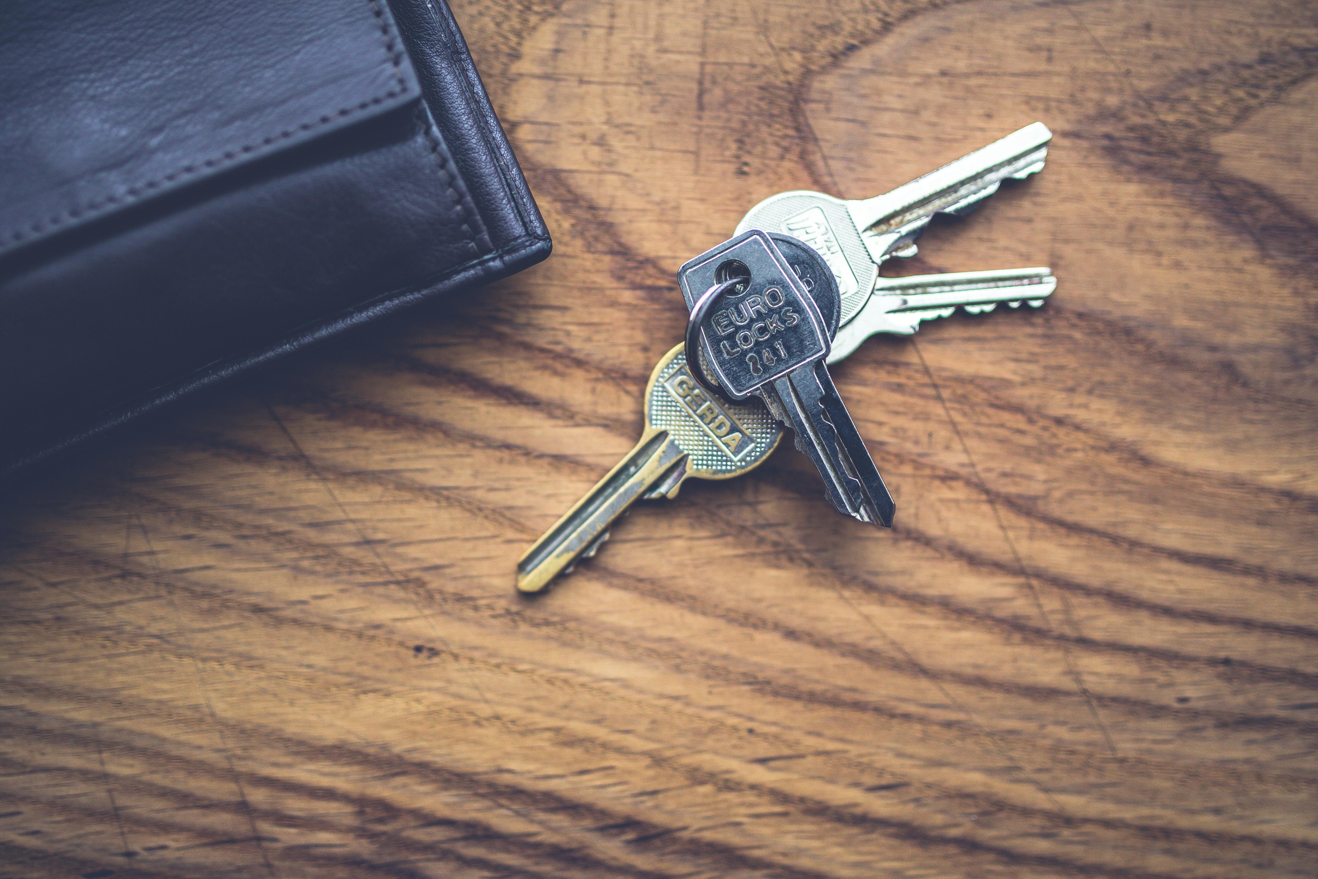 Modern keys next to leather wallet on wooden table